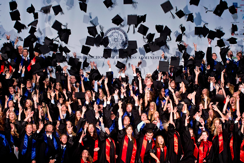 Absolvent_innen werfen Hüte in die Luft bei der Graduierung